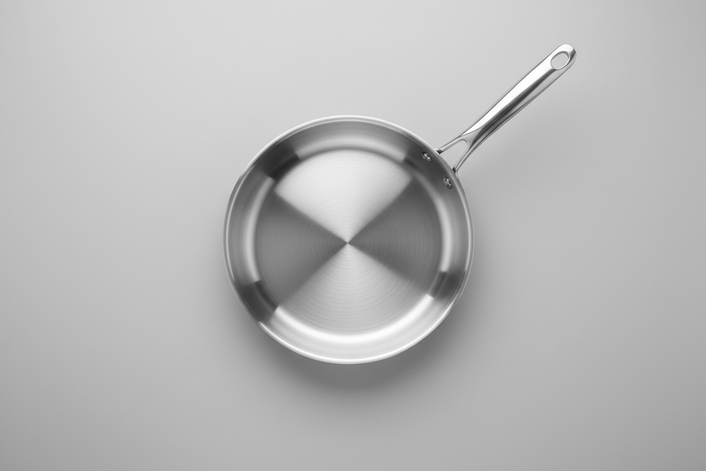 Photorealistic overhead, straight top-down product image of a frying pan centered in the frame. The pan surface is completely clean, smooth, and polished with a glossy non-stick finish. No stains, residue, or discoloration. Even reflections across the surface, crisp edges, and a brand-new appearance. Neutral studio background, soft balanced lighting, ultra-sharp focus, high realism, e-commerce product photography style, no text, no logos.